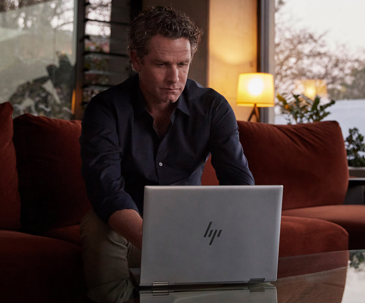 Man working on an HP laptop from home in the evening.