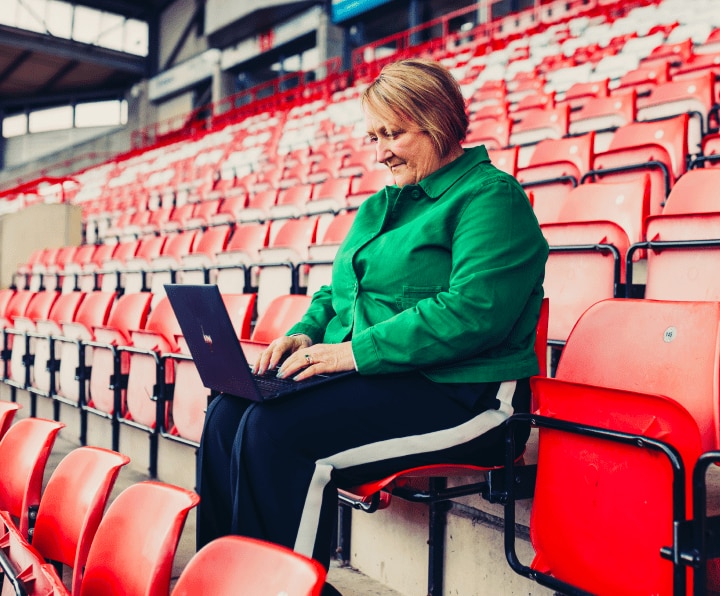 Female Wrexham employee using HP laptop in Wrexham stadium seat