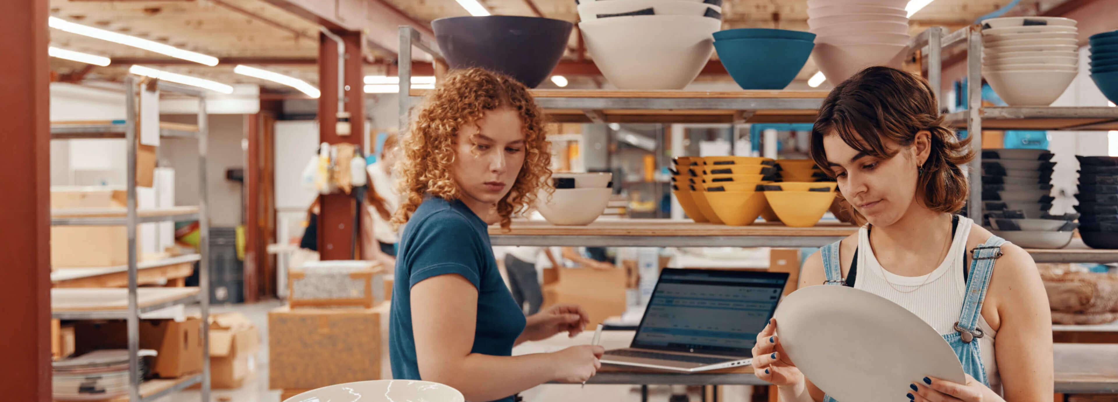 Two women working together in a pottery business with an HP laptop