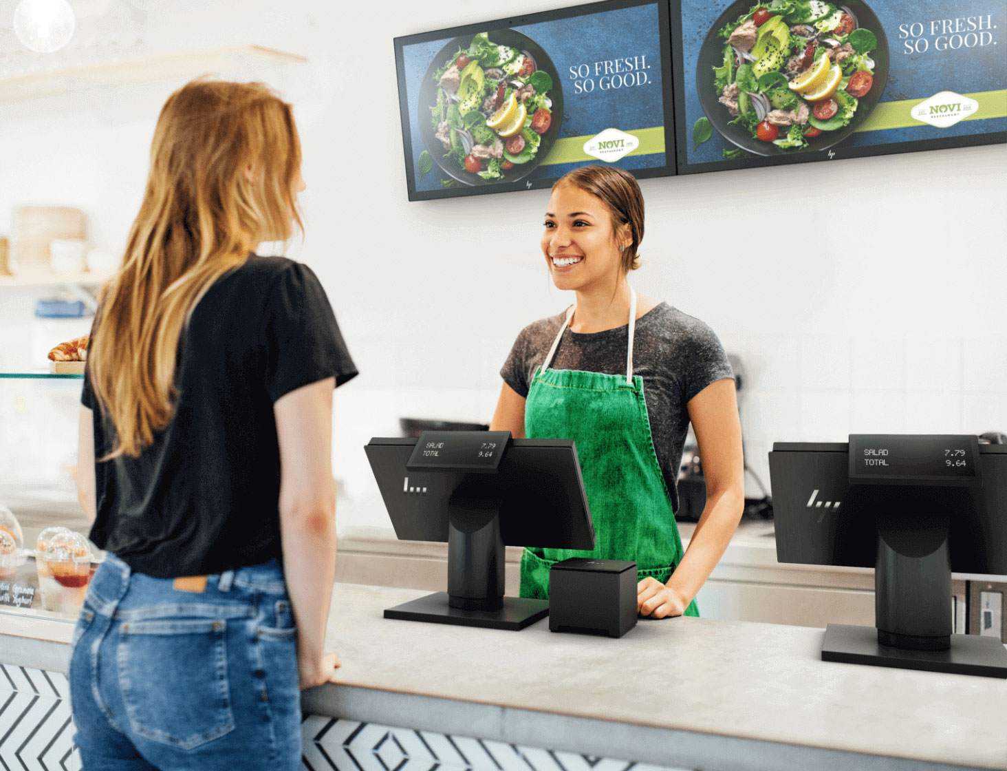 Restaurant worker taking an order from a customer, HP Engage point of sale systems and an HP receipt printer are at the checkout counter